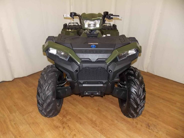 a green four - wheeler is parked on a wooden floor