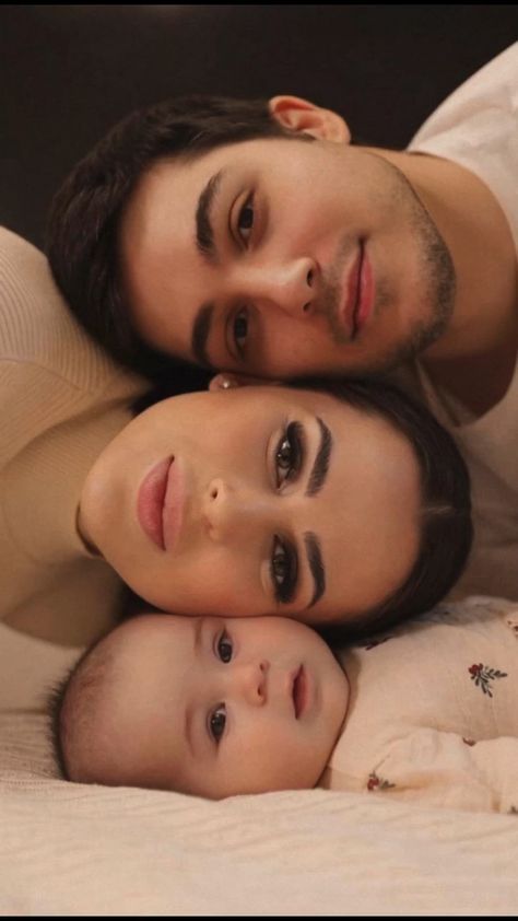 two adults and a child laying on a bed