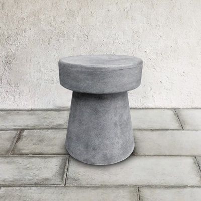 a concrete stool sitting on top of a tiled floor