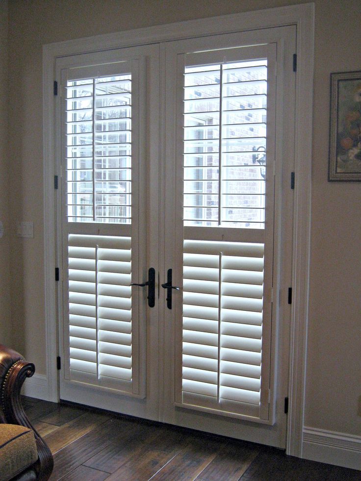 a living room with white shuttered doors and wooden floors in front of a couch