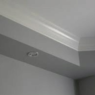 the corner of a room with a white ceiling and light fixture on it's side