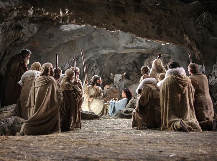 a group of people sitting in front of a cave