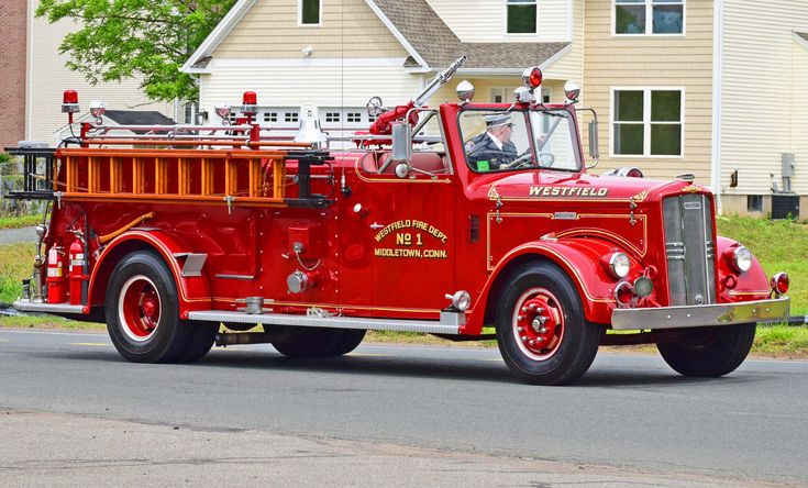 an old red fire truck driving down the street