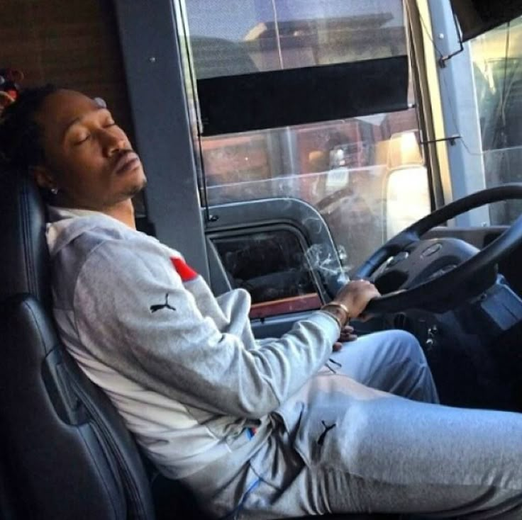 a man sitting in the driver's seat of a bus with his eyes closed