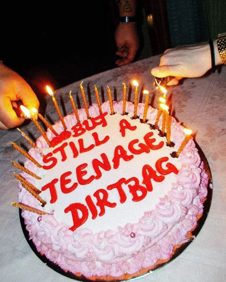 someone lighting candles on a birthday cake with the words still a teenage dirtbag written on it