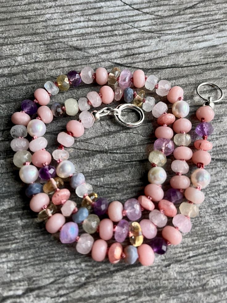 This lovely, delicate gemstone necklace contains gemstones in shades of pastel pink and purple with occasional hints of golden yellow. Peruvian opal, moonstone, lavender moonstone, citrine, amethyst, freshwater pearl, morganite, agate, lavender opal, rhodochrosite, and spinel. Finished with a sterling silver clasp. The gems in this necklace are a more delicate 5-6mm size, and are individually hand knotted onto rose colored silk. Necklace is about 18.25 inches in length, and is one of a kind. You Pink Opal Necklace, Pink Quartz Necklace, Shades Of Pastel Pink, Textile Accessories, Pastel Pink And Purple, Shades Of Pastel, Pink Gemstone Necklace, Opal Moonstone, Lavender Opal