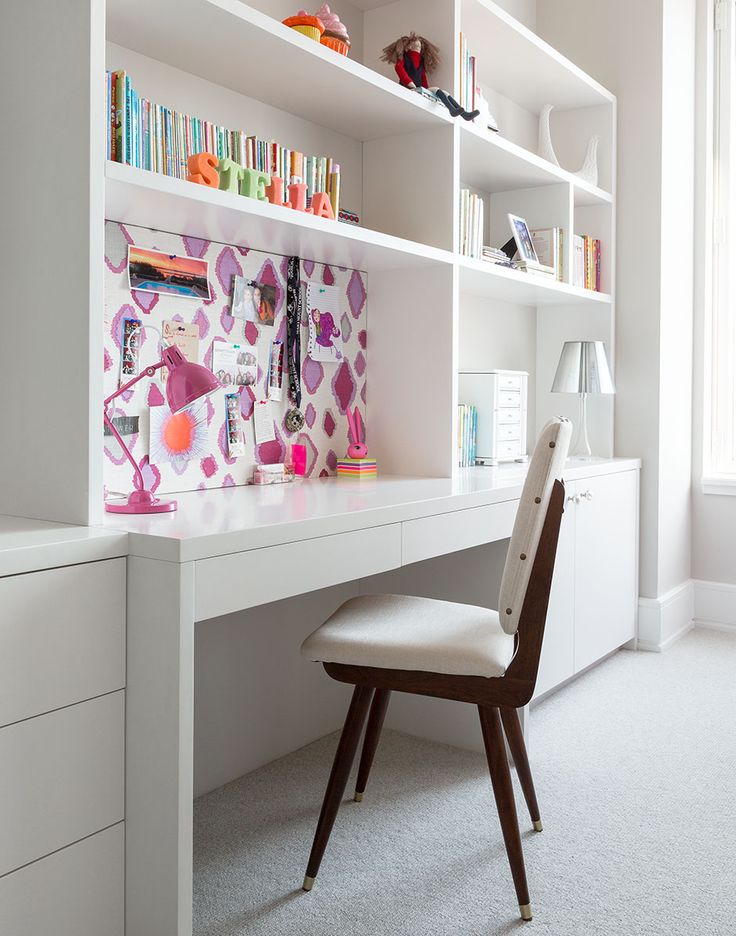 a white desk and chair in front of a book shelf with books on it's shelves