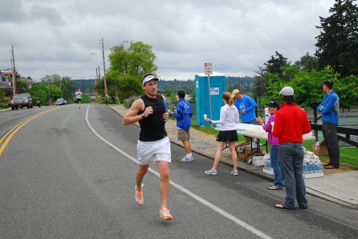 a man running down the road with people watching him