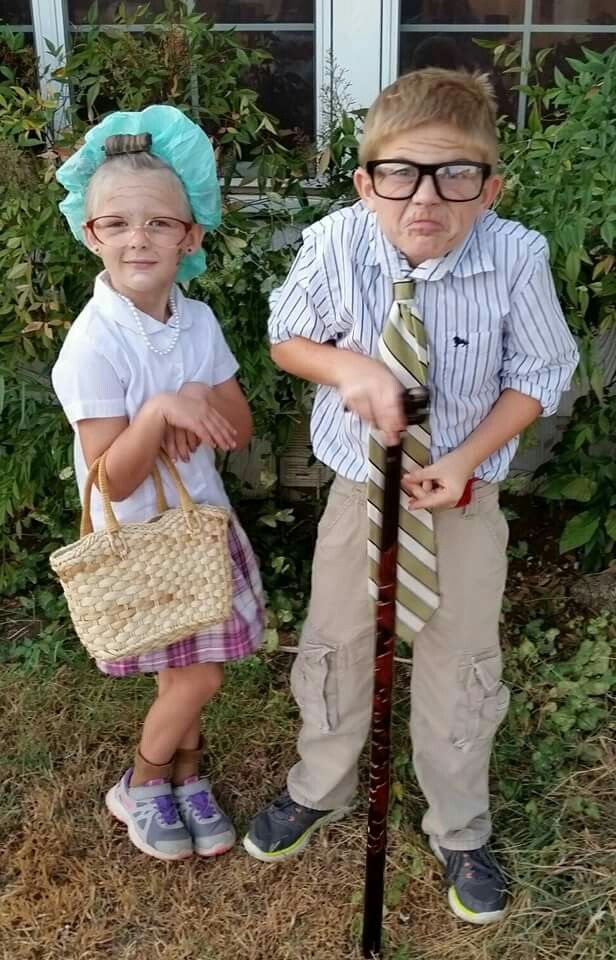 two young children standing next to each other holding onto a stick with a tie on it