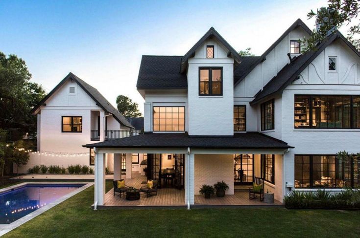 a large white house sitting next to a swimming pool in the middle of a lush green yard