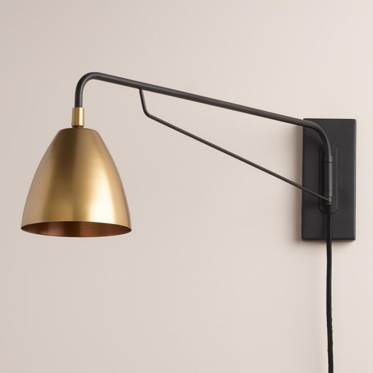 a black and gold wall light next to a white wall with a lamp on it