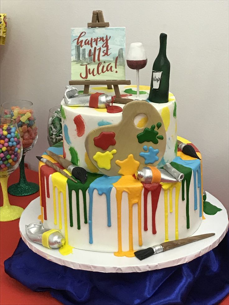 a birthday cake is decorated with colorful icing and an artist's palette on top