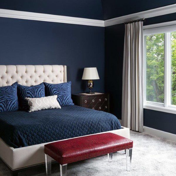 a bedroom with blue walls and white bedding has a bench in front of it