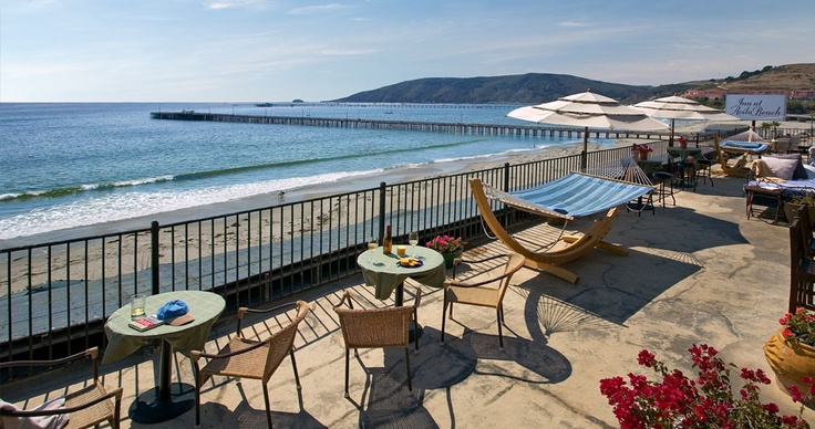 an outdoor patio with tables and chairs overlooking the ocean