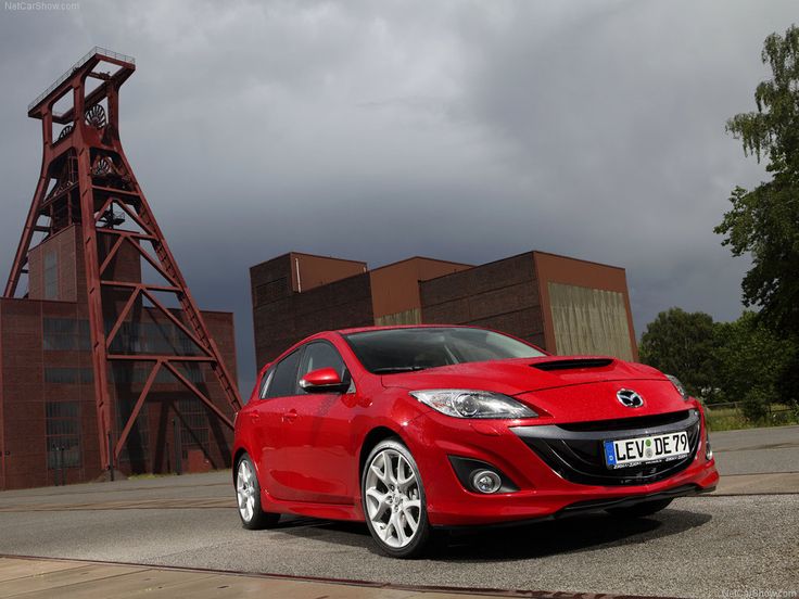 a red car parked in front of a tall tower