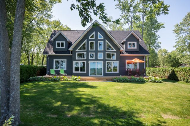 a large house sitting in the middle of a lush green field next to a tree