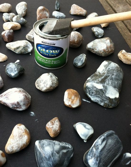 a can of paint sitting on top of rocks next to a wooden stick and hammer