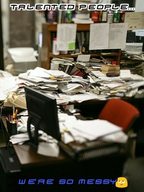 an office desk covered in papers and clutter with a computer on top of it