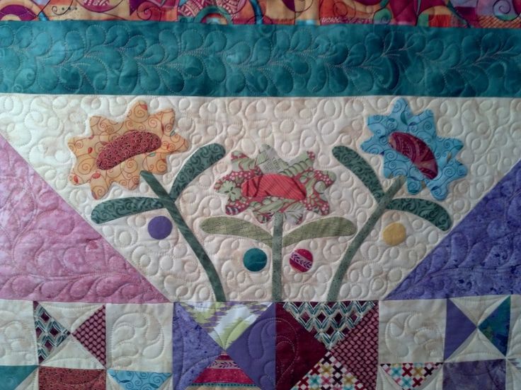 a quilted wall hanging with flowers on it