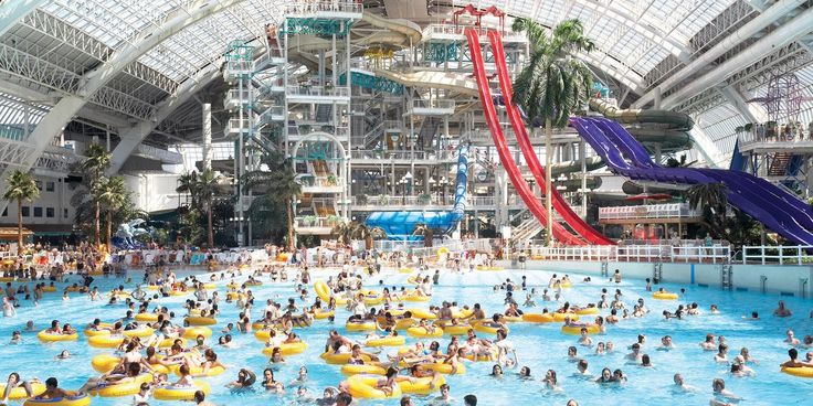 an indoor water park filled with people swimming and riding rafts in ...