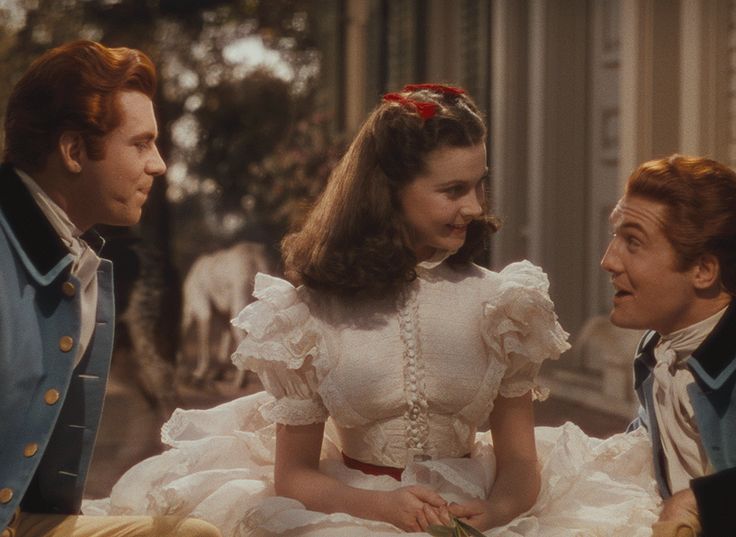 the young man and woman are sitting next to each other in front of an old fashion dress