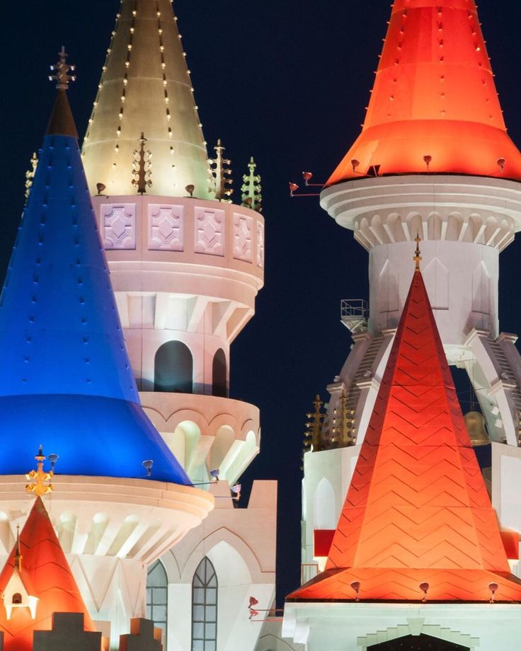 some very colorful buildings lit up at night with bright lights on the top and bottom