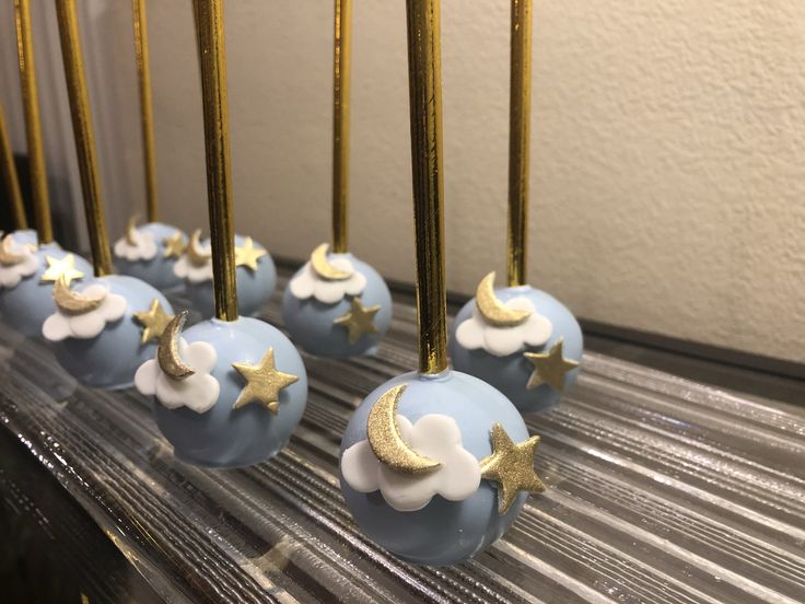 some blue cake balls with gold stars and clouds on them are lined up in rows