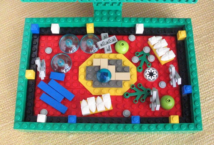 two lego trays filled with toys on top of a carpeted floor next to each other