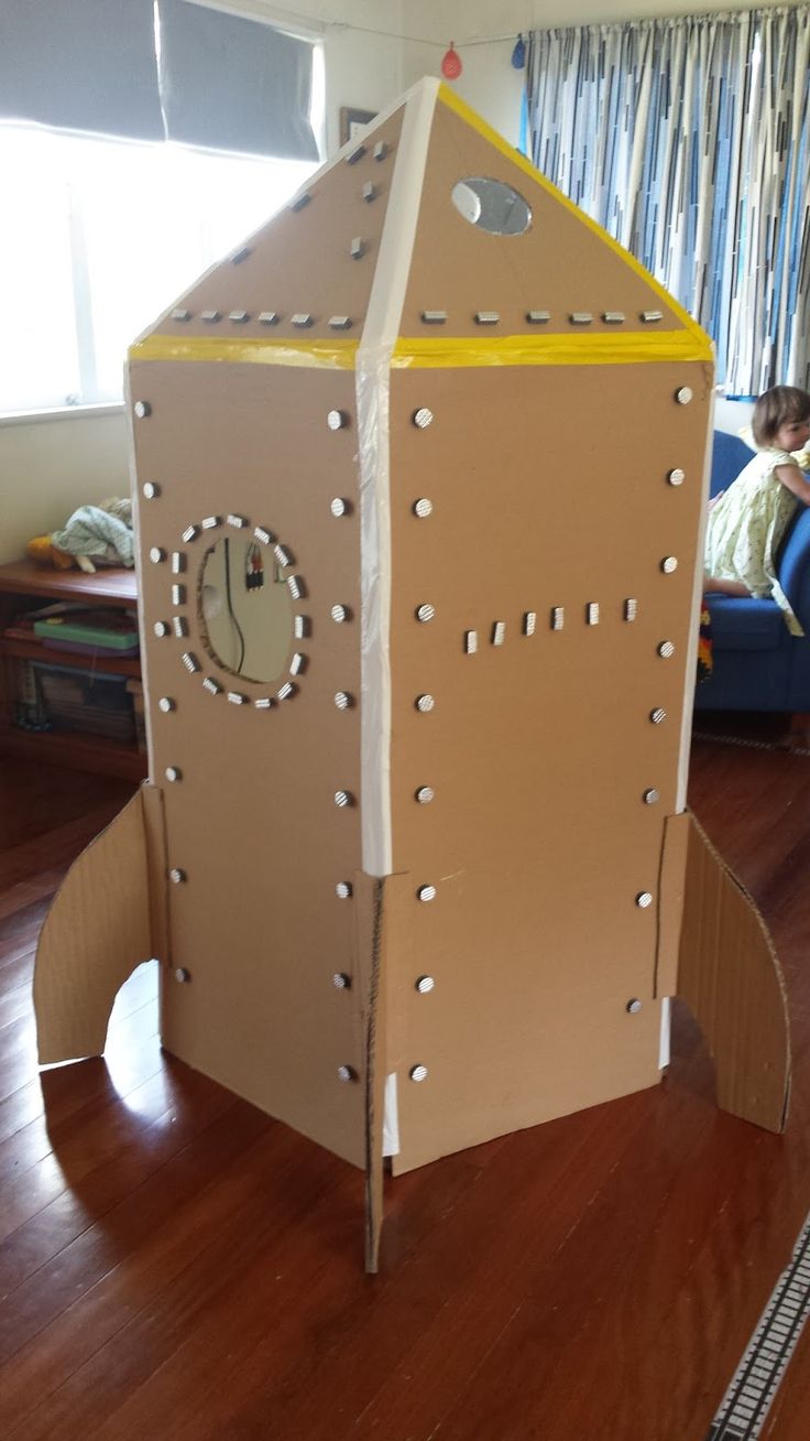 a cardboard rocket ship sitting on top of a wooden floor