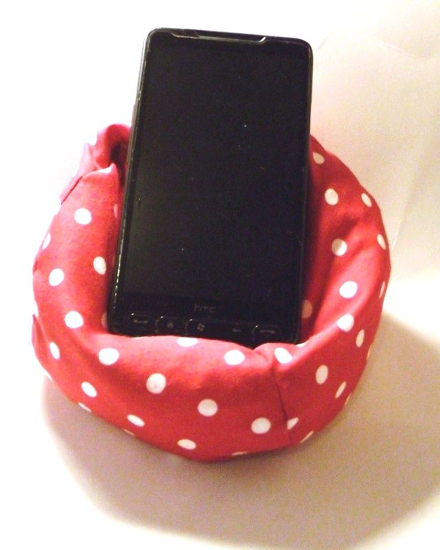 a cell phone sitting on top of a red polka dot fabric holder with white dots