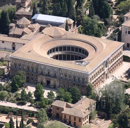 an aerial view of a large building in the middle of trees and buildings around it