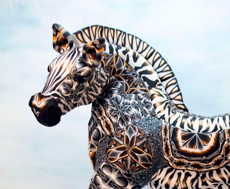 a statue of a zebra standing on top of a lush green field next to a blue sky