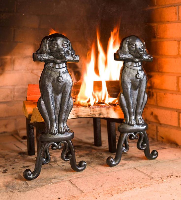 two metal dogs sitting on stools in front of a fire place with flames burning behind them