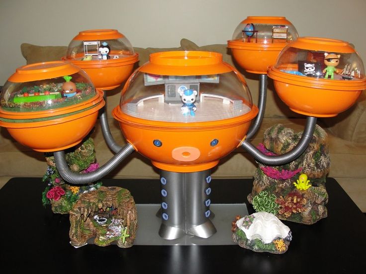 an orange toy machine with five bowls on it's sides and four small toys in the middle