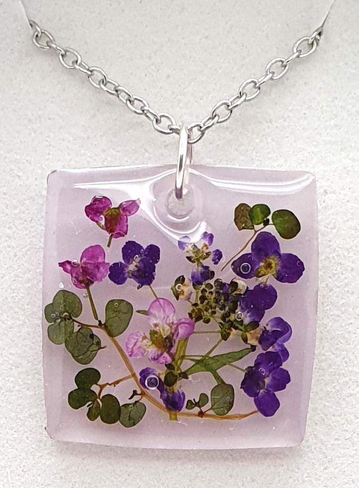 a square glass pendant with purple flowers on it