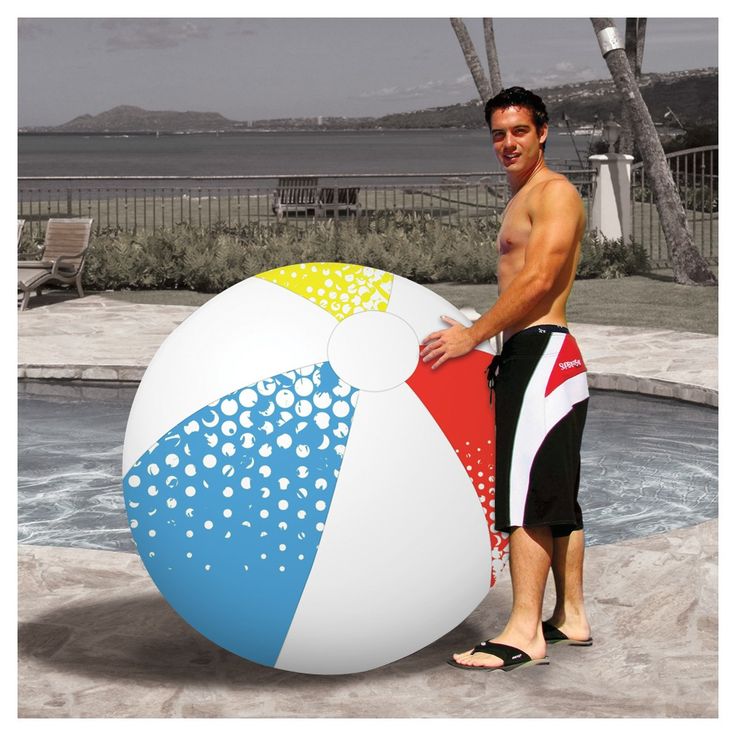 a man standing next to a large beach ball