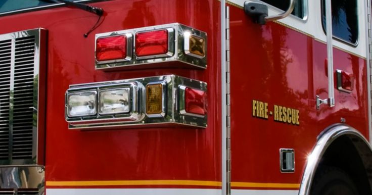 the front end of a red fire truck with its lights on and chrome grills