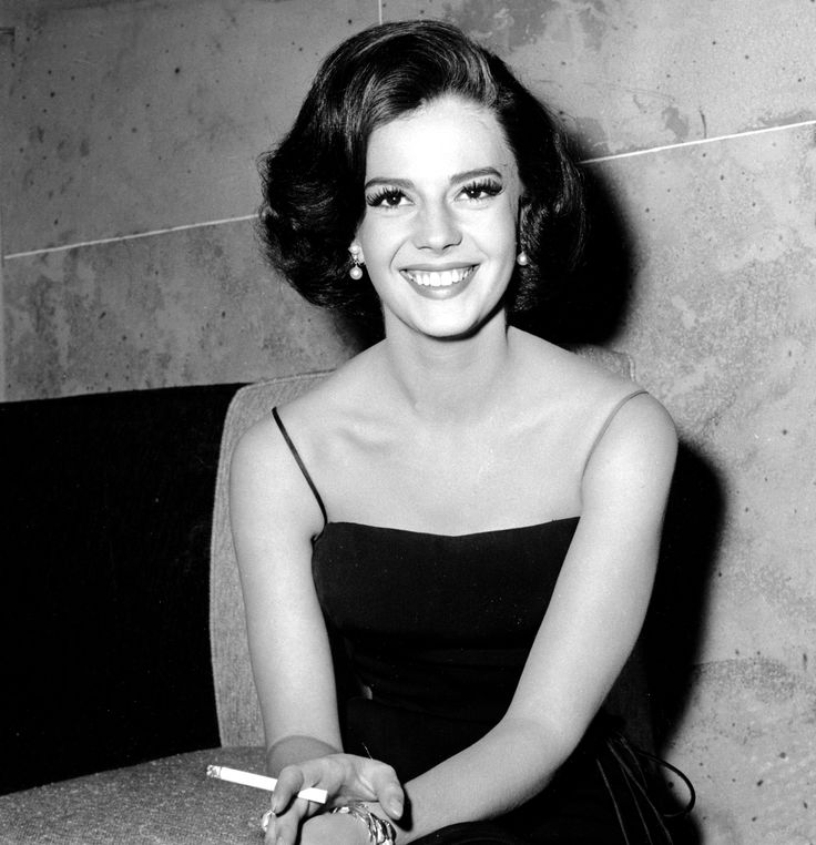 a black and white photo of a woman in a strapless dress smiling at the camera