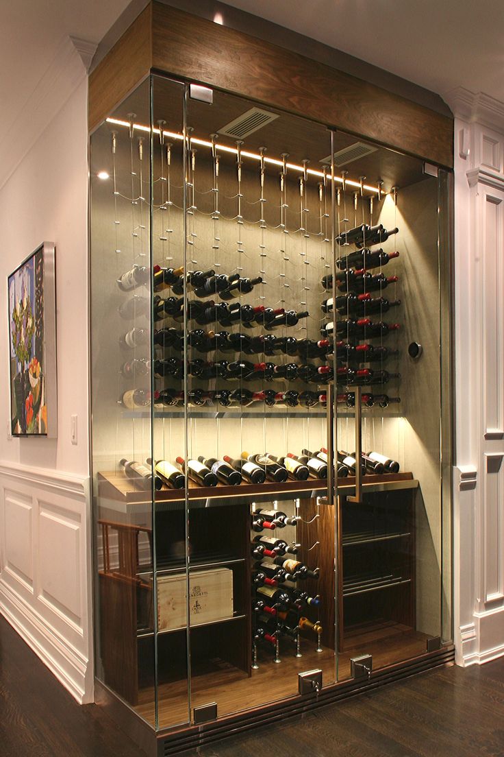 a wine cellar with many bottles and glasses on it's glass shelves in front of the wall