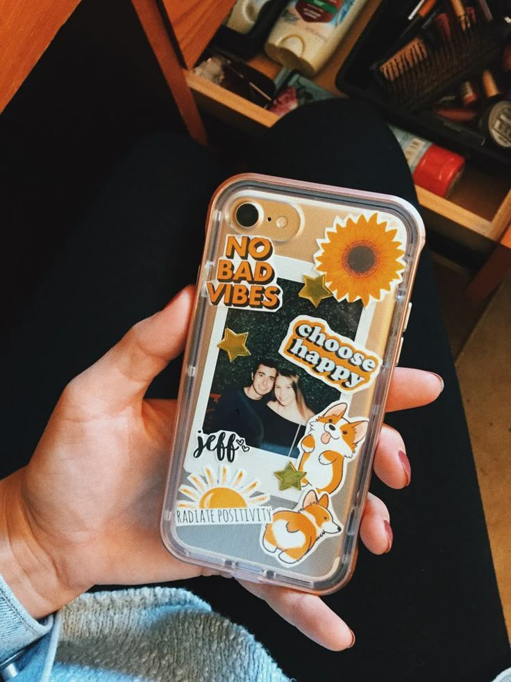 a person holding up a cell phone case with stickers on it