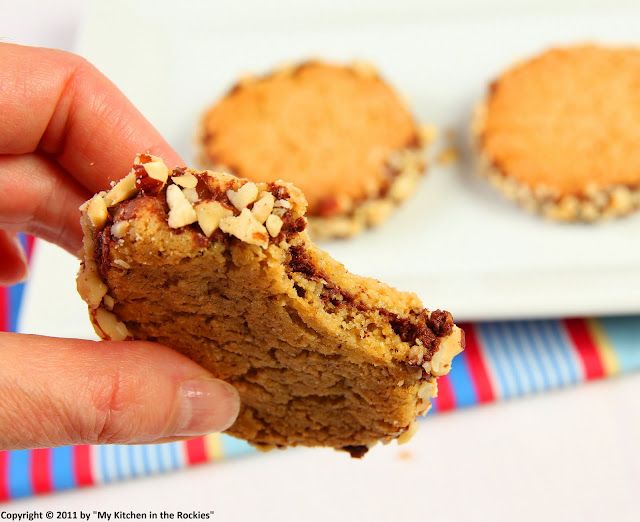 a hand holding a half eaten cookie on a plate