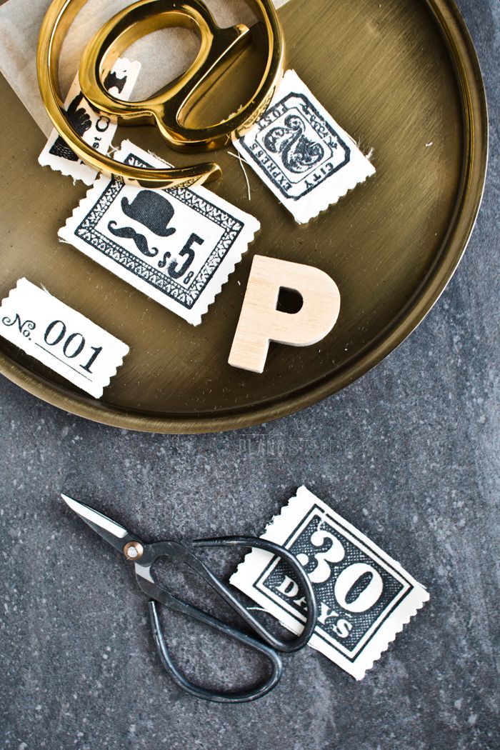 scissors and stamps on a metal tray with the letter p cut out to look like postage