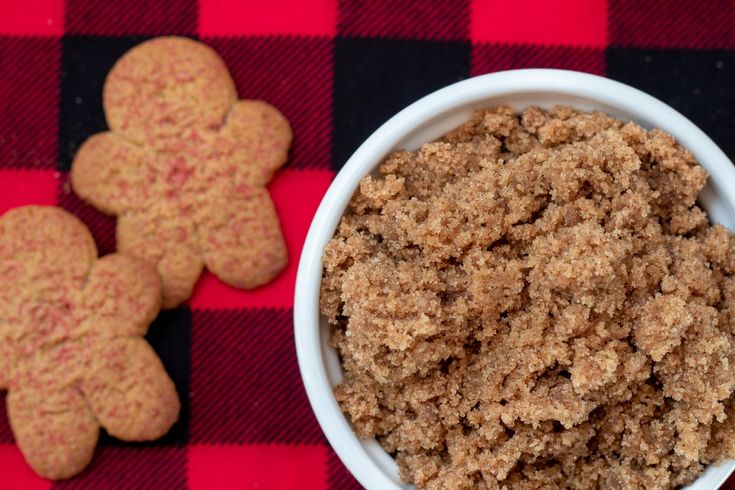 a bowl of oatmeal next to some cookies on a red and black checkered tablecloth