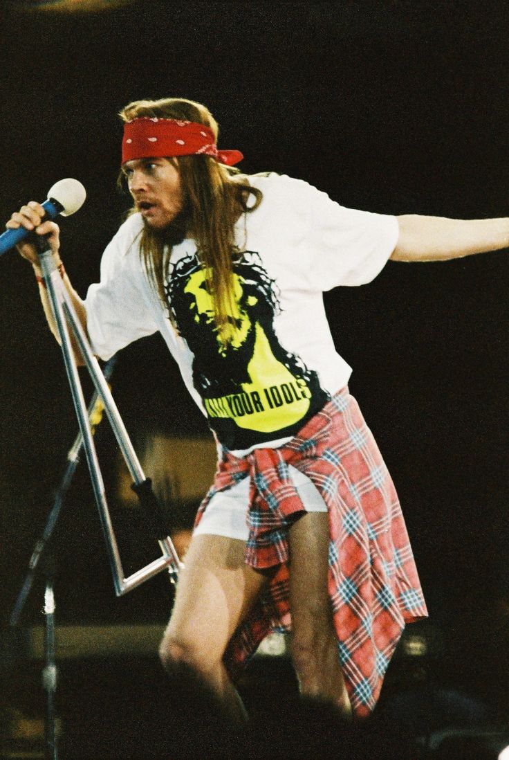 a man with long hair wearing a bandana and holding a microphone in his hand