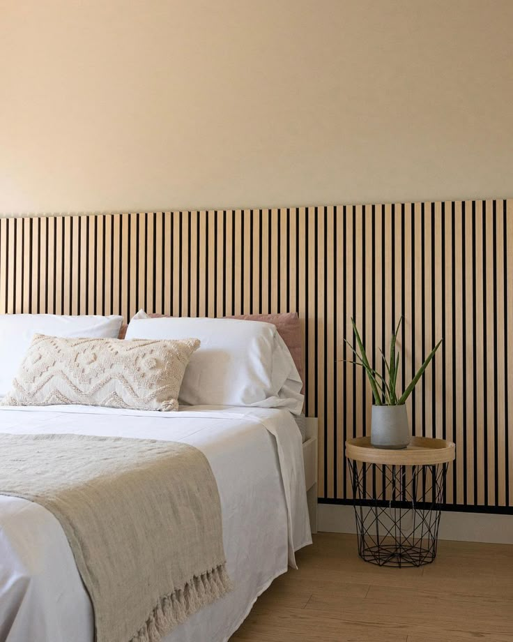 a white bed sitting in a bedroom next to a wall with vertical stripes on it