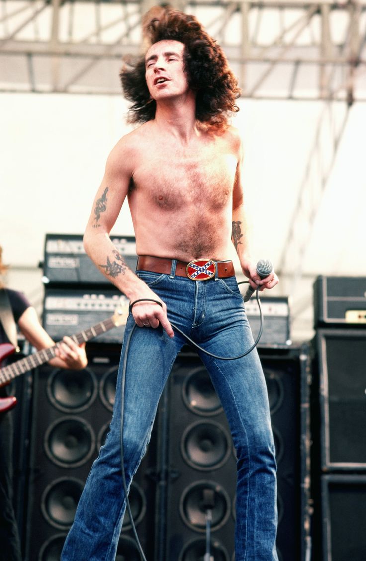 a shirtless man with long hair standing on stage