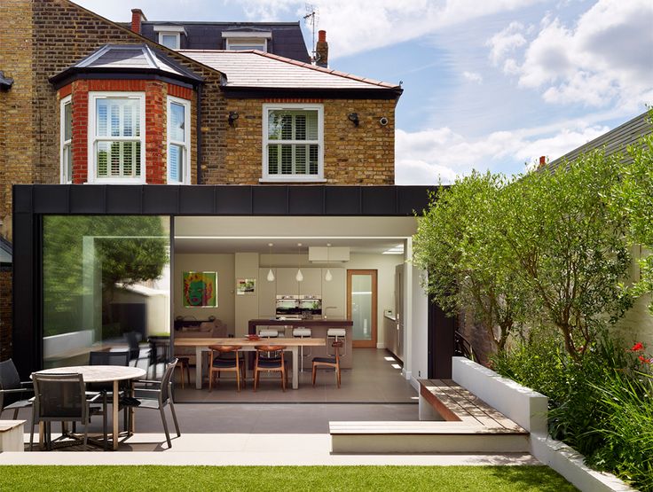 an outdoor dining area in front of a brick building with glass doors and windows on the side