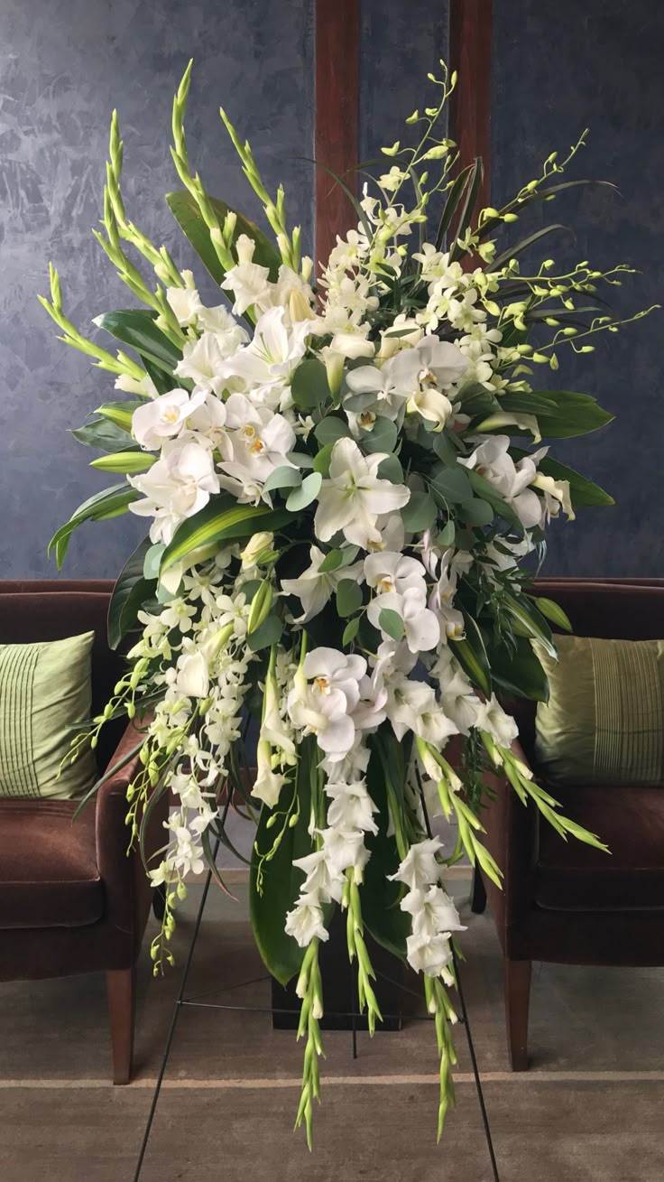 a large bouquet of white flowers sitting on top of a wooden table next to a brown chair