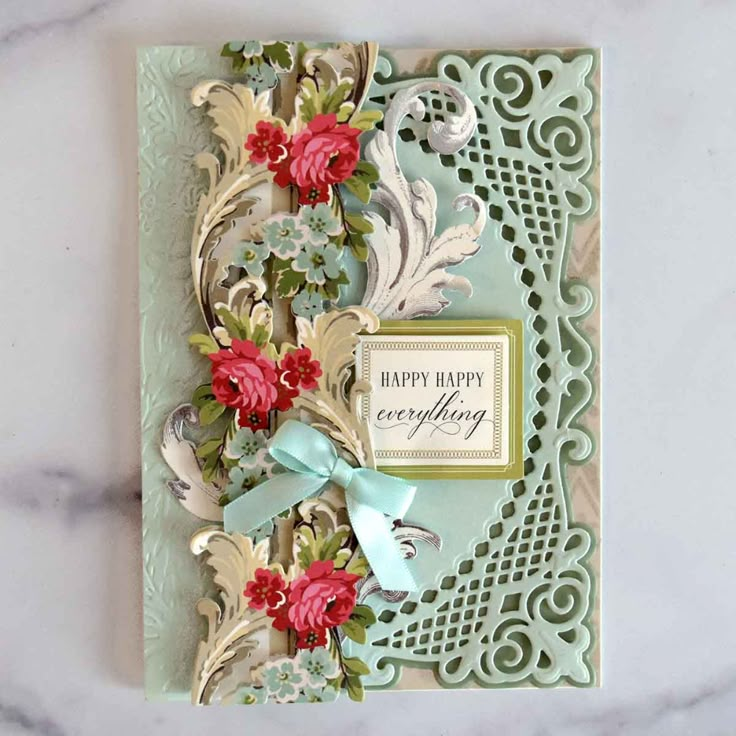 a handmade greeting card with flowers and ribbon on the front, sitting on a marble surface