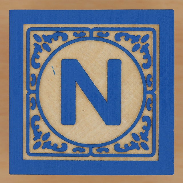 a wooden block with the letter n in it's center and an ornate border